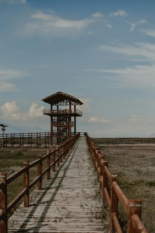 wooden walkway to small structure in open grassy area