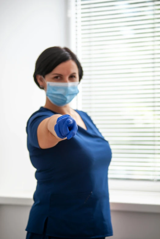 the woman with a surgical mask on is pointing to someone