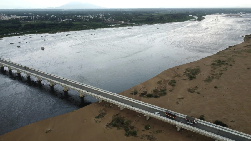 two vehicles traveling along a highway with bridge in the distance