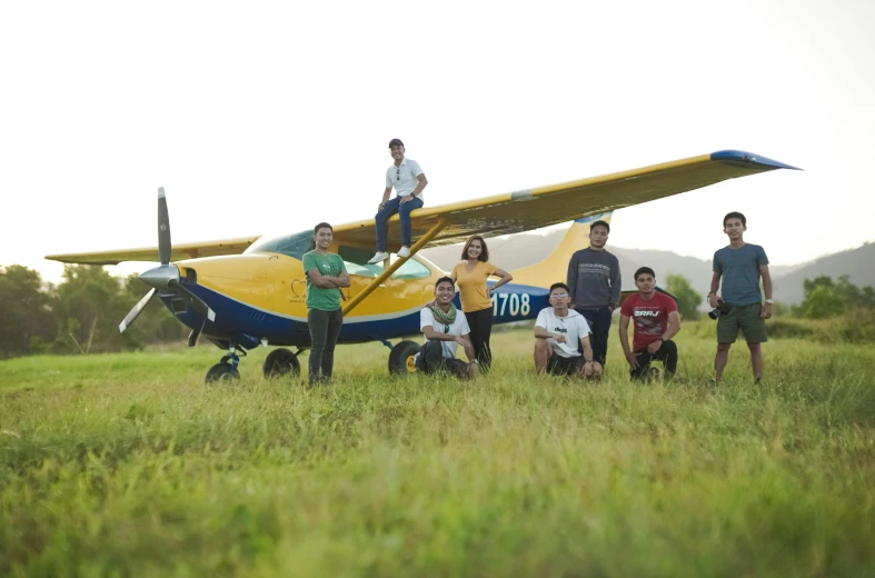 a group of people standing around a small yellow plane