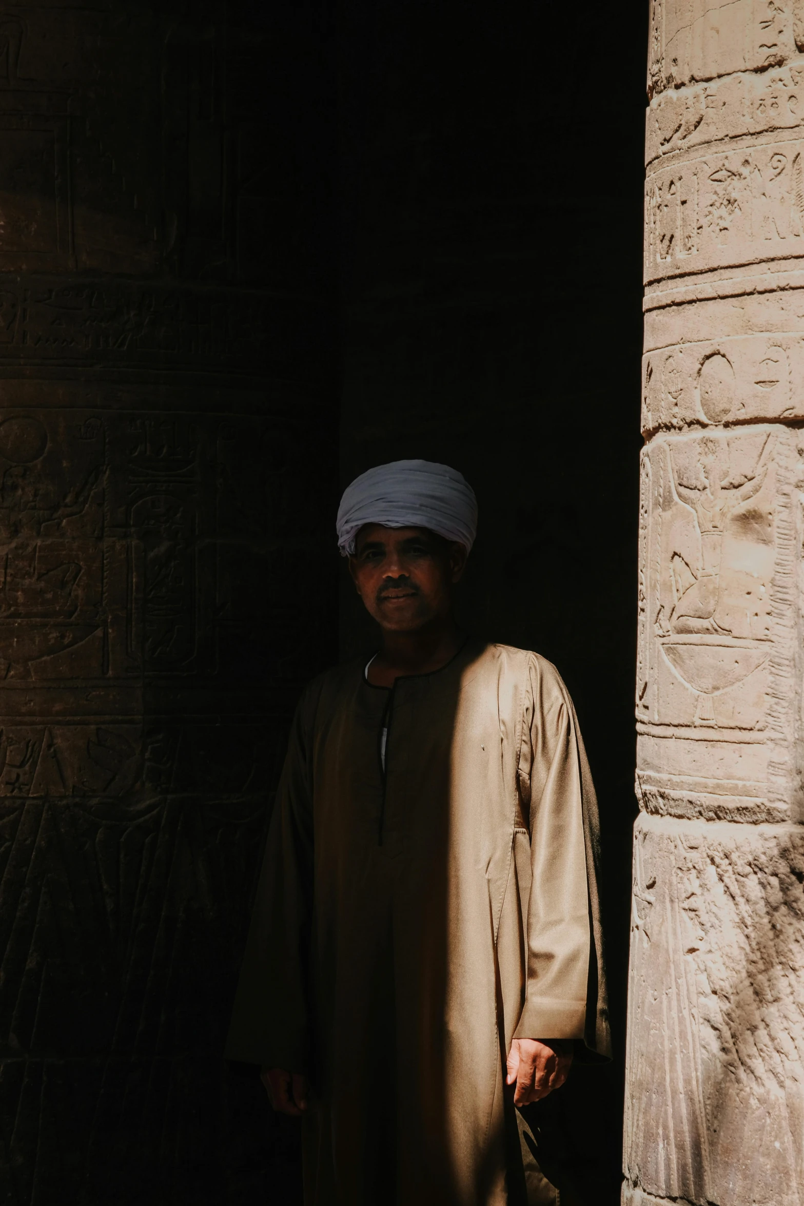 a man stands in front of an old carved doorway