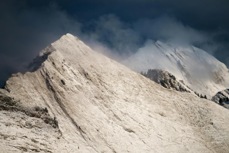 a snowy mountain peak surrounded by a cloud in the sky