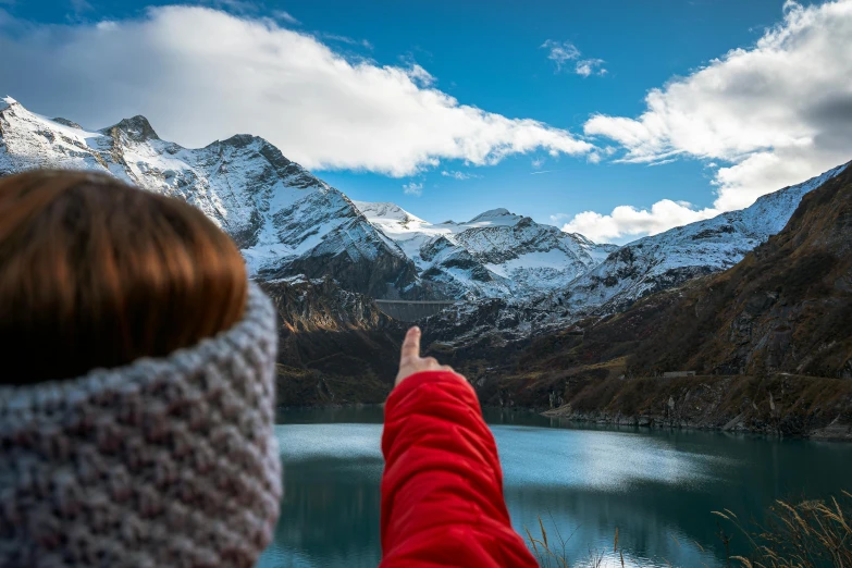 a woman pointing her finger at snow covered mountains