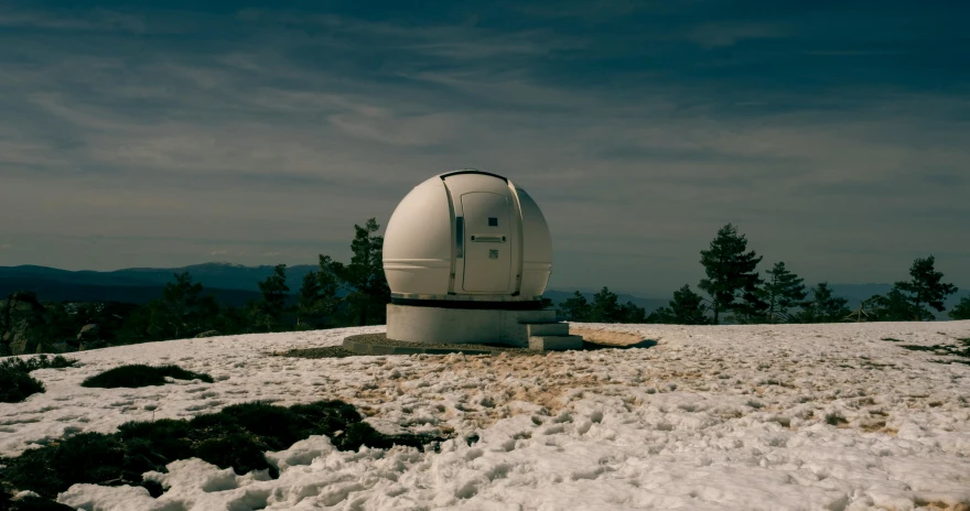 a small structure stands in the snow at the top of a mountain