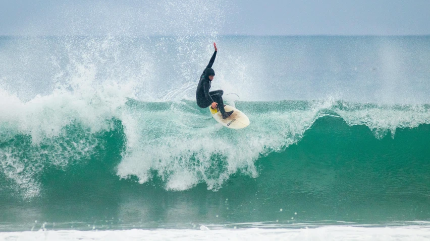 man flying over wave on white surfboard