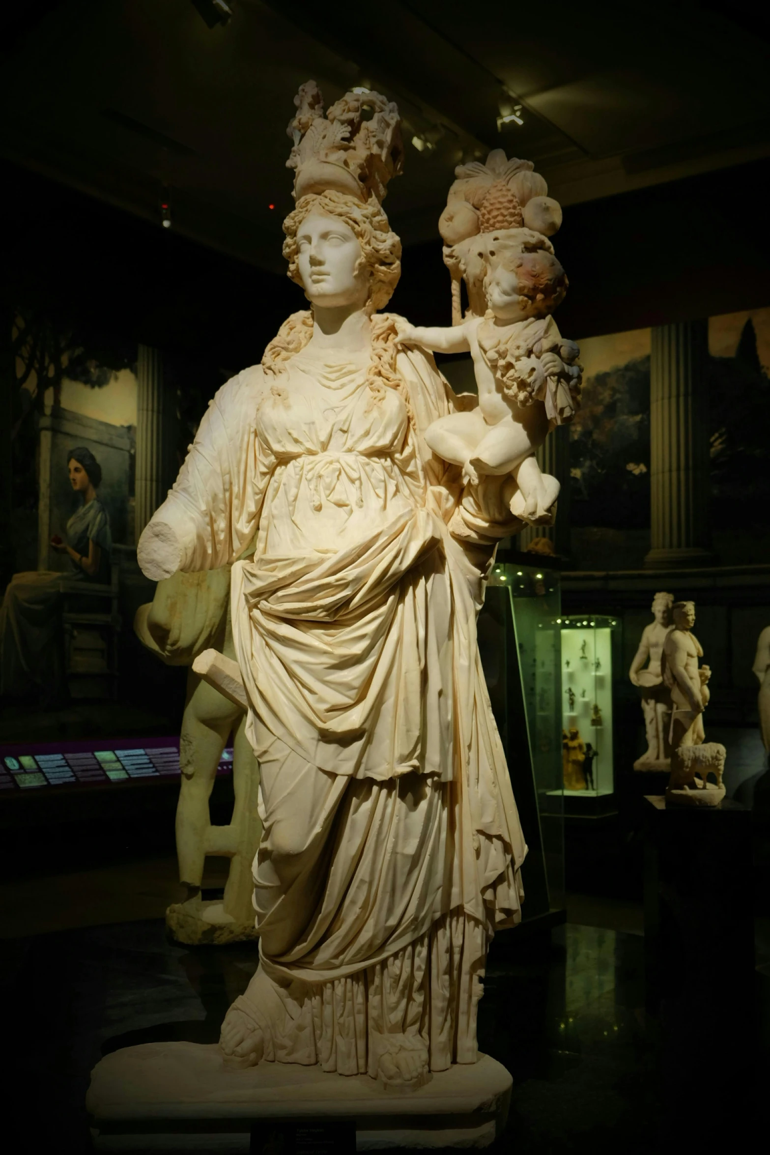 a sculpture with flowers in her hair stands next to a sculpture