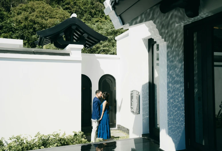 a couple in blue posing for a po in front of their house