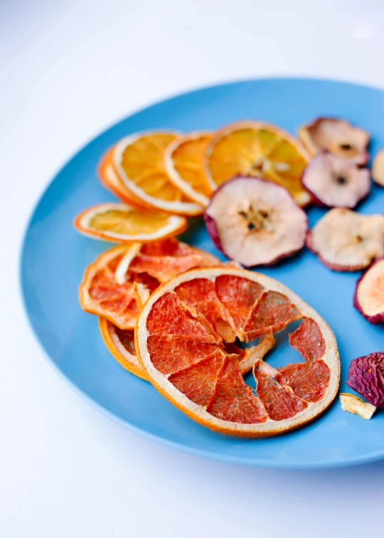 peeled sliced fruits arranged on blue plate with white background