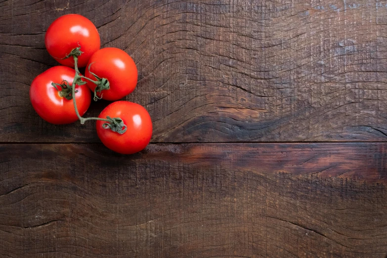 four tomatoes on a wooden table