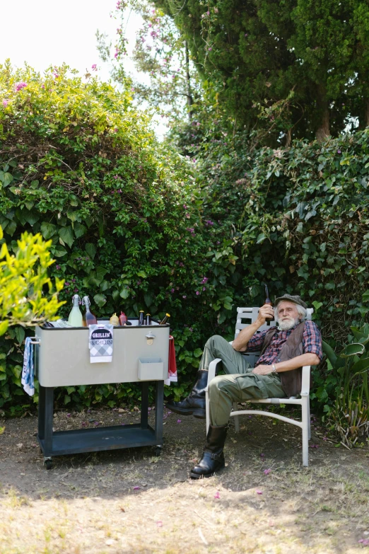 man in chair sitting outside with drinks and wine on the tray