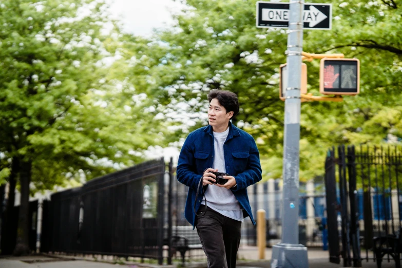 young man walking on a city street holding a cell phone