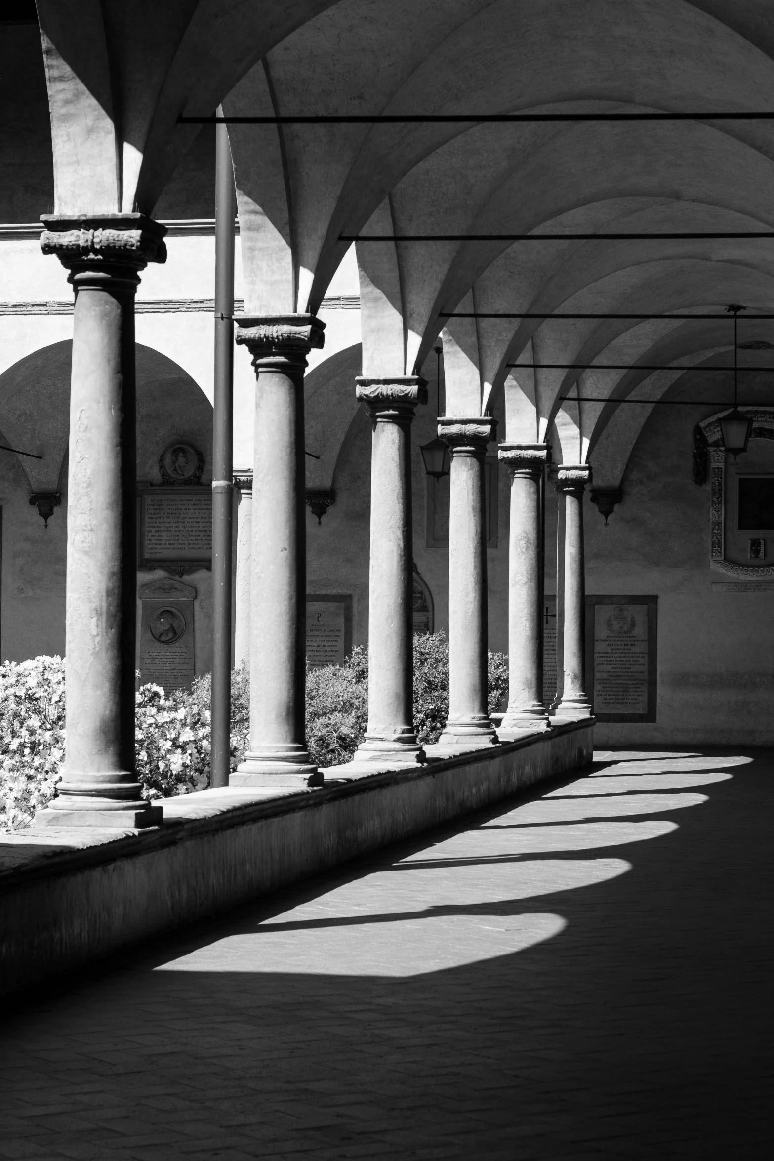 black and white po of arched pillars with pots in the background