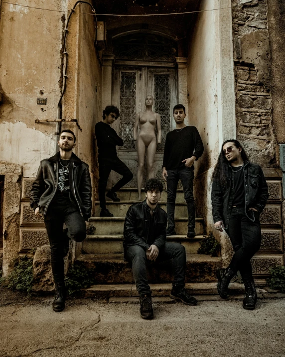 four men sit outside an old brick building