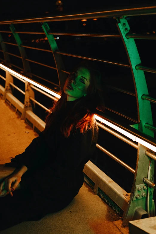 a woman with long hair sitting down on a bridge