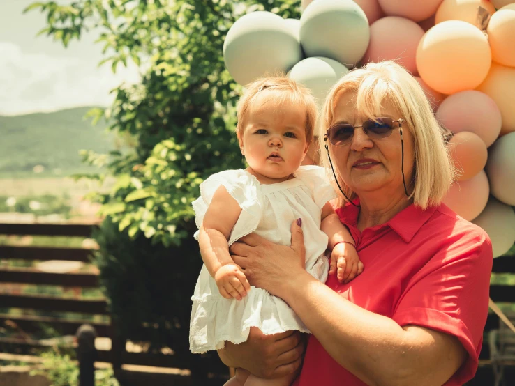 an older woman holding a small child near balloons