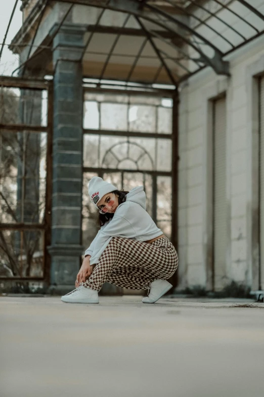 a young person crouched in a room with a window