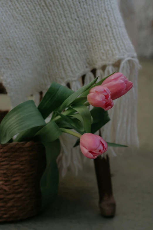 pink flowers in a basket in front of a wooden chair