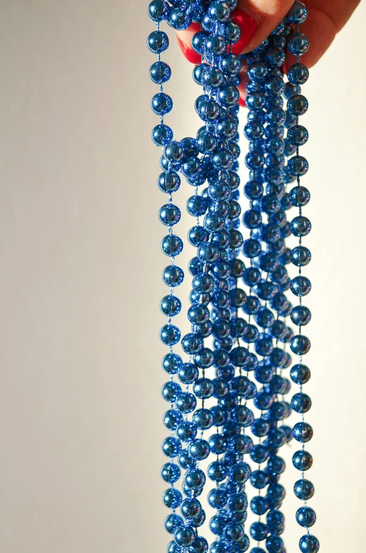 someone is holding on to blue beads by a string