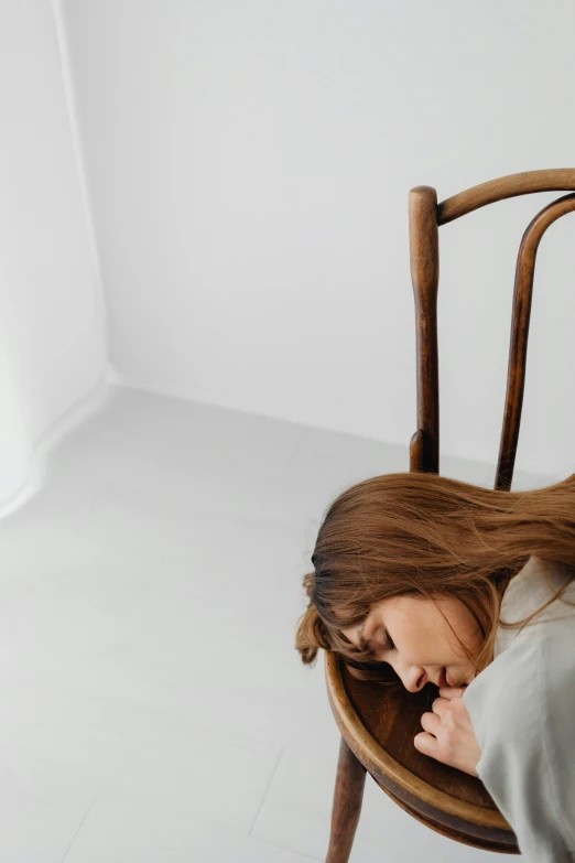 a young lady sitting in a chair with her head on a table