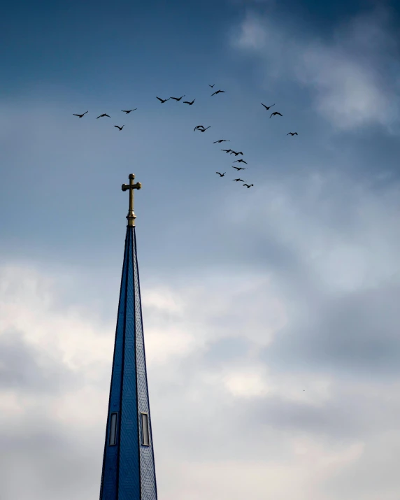 a church steeple with birds flying above it