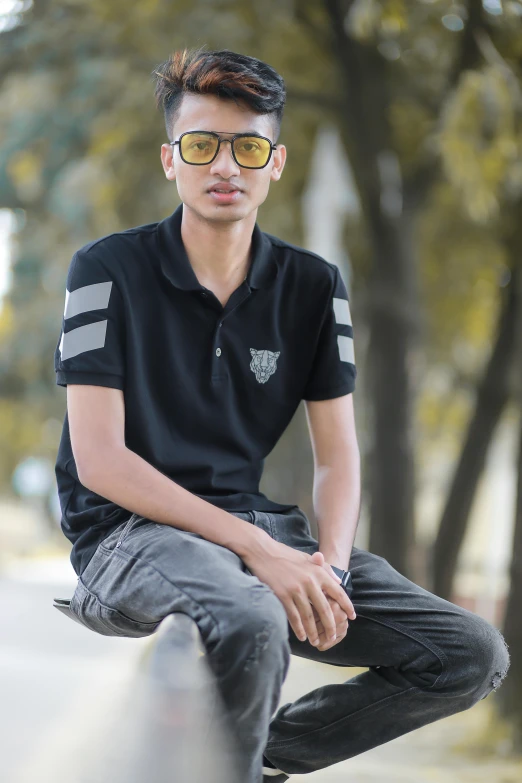 a boy is wearing a polo shirt, sitting on a wall