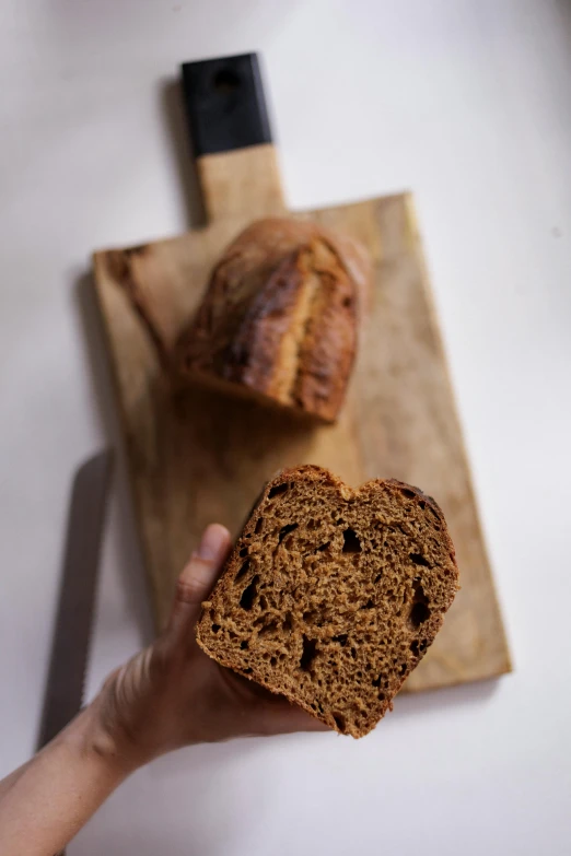 a person holding a piece of bread near a knife