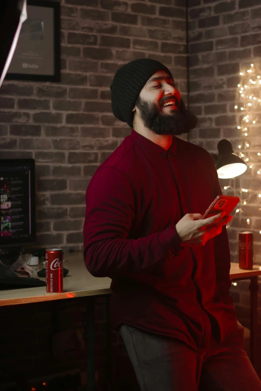 a man in a red shirt sits next to a light and some soda cans