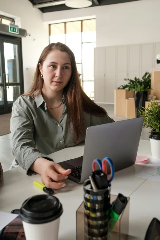 a young lady looks at the camera while using a laptop