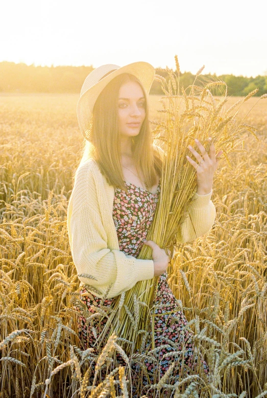 woman in hat and floral dress standing in wheat field