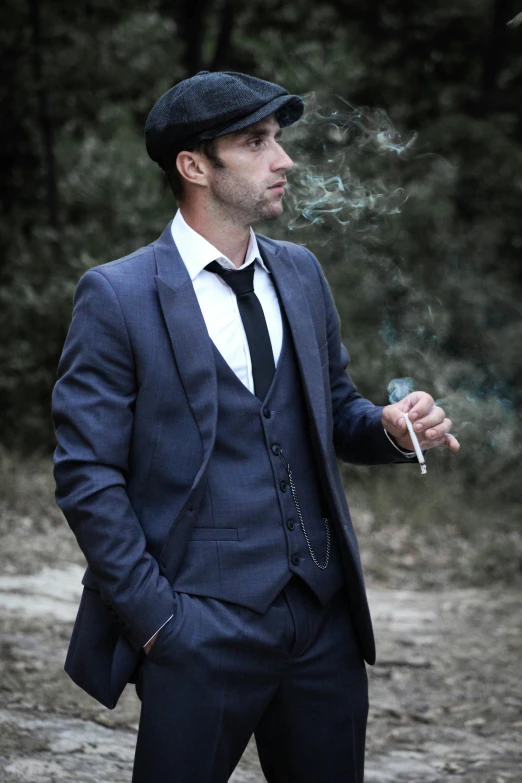 a man smoking a cigarette while wearing a hat and suit