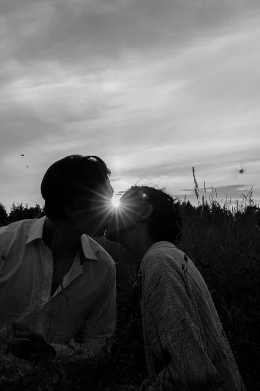 two young people kissing while the sun is setting