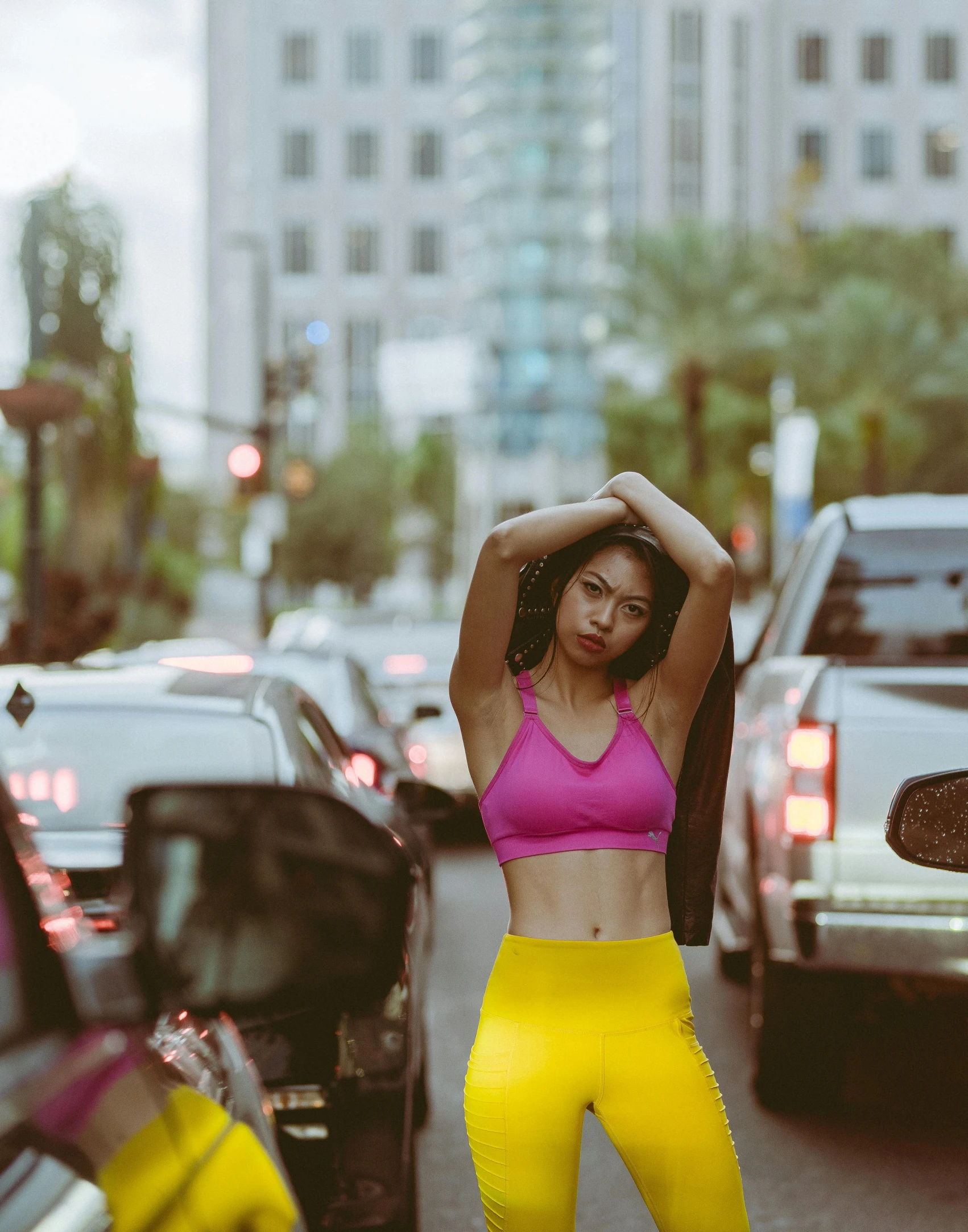 a woman posing on a busy street in a bikini top and neon yellow pants