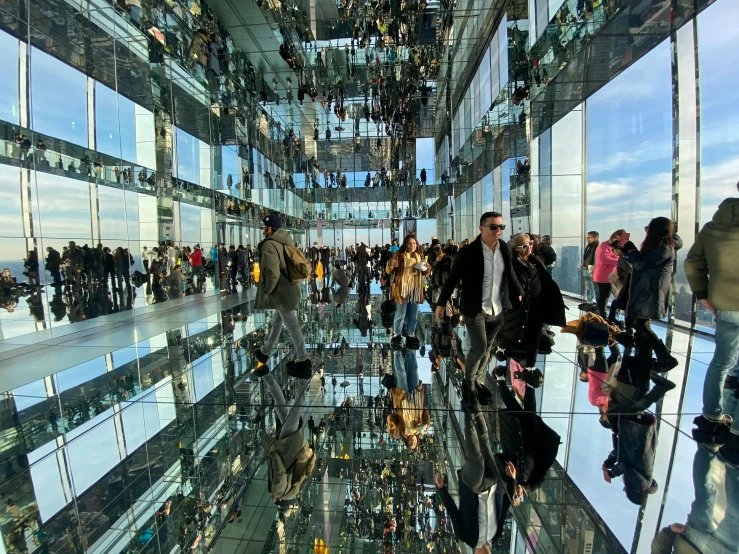 people walking through the reflections of their surroundings in the building