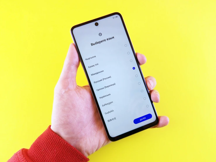 a person's hand holding a cell phone on top of a yellow background