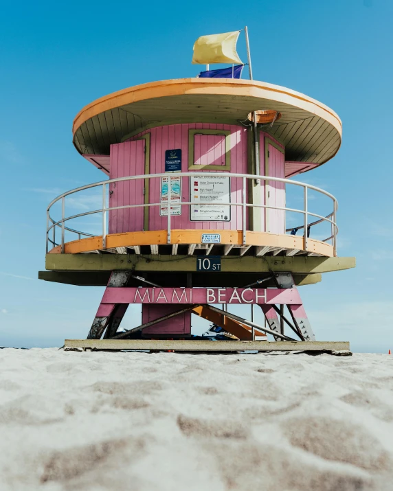 pink lifeguard stand on the beach with a blue sky in the background