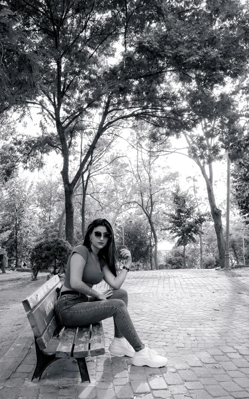 a young lady sitting on a bench near some trees