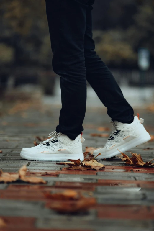 the bottom of the shoes of a person standing on a walkway in front of trees