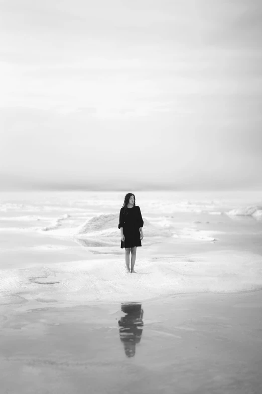 a black and white po of a person standing at the edge of the water