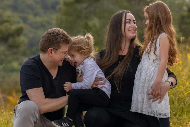 four children smiling at each other while sitting on the ground