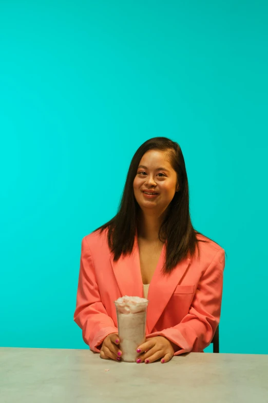 the smiling woman is holding a beverage next to a stack of folded napkins