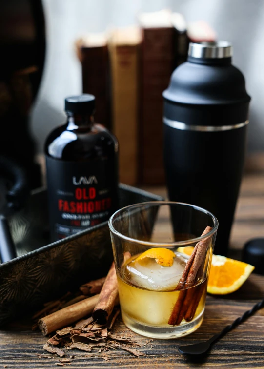 a drink on a table with cinnamon, an orange and a bottle