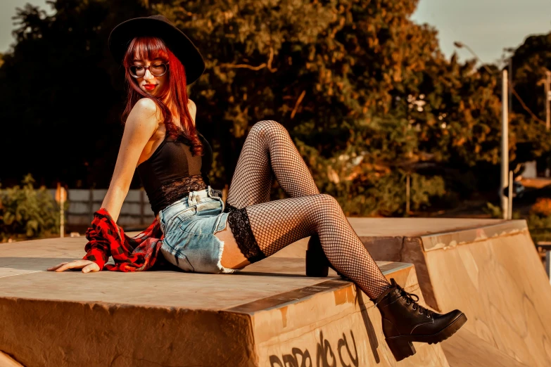 a beautiful young lady with red hair sitting on top of a skateboard ramp