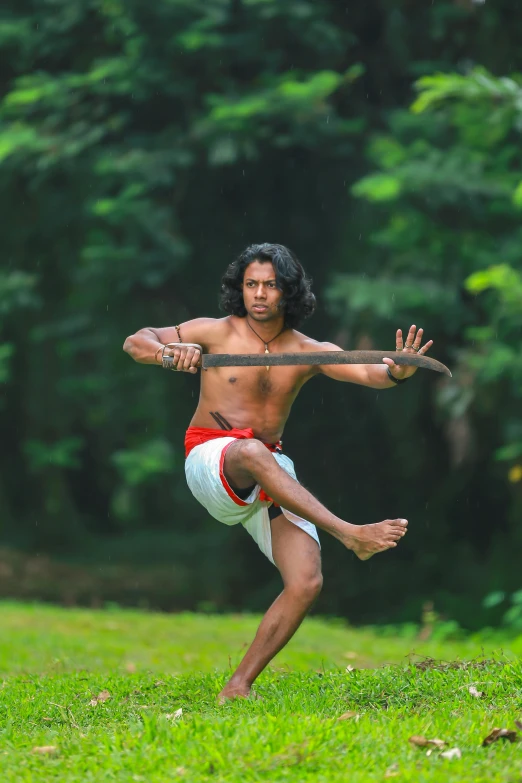 a man with one leg on another leg standing in the grass