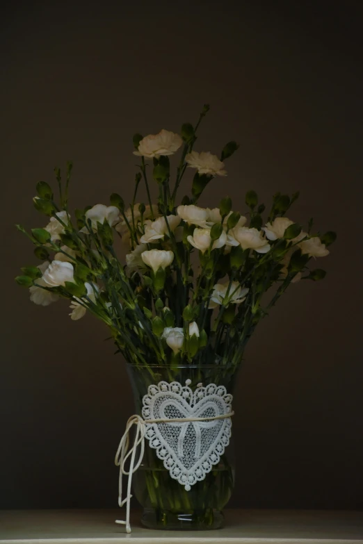 a vase with flowers and lace in it on a counter