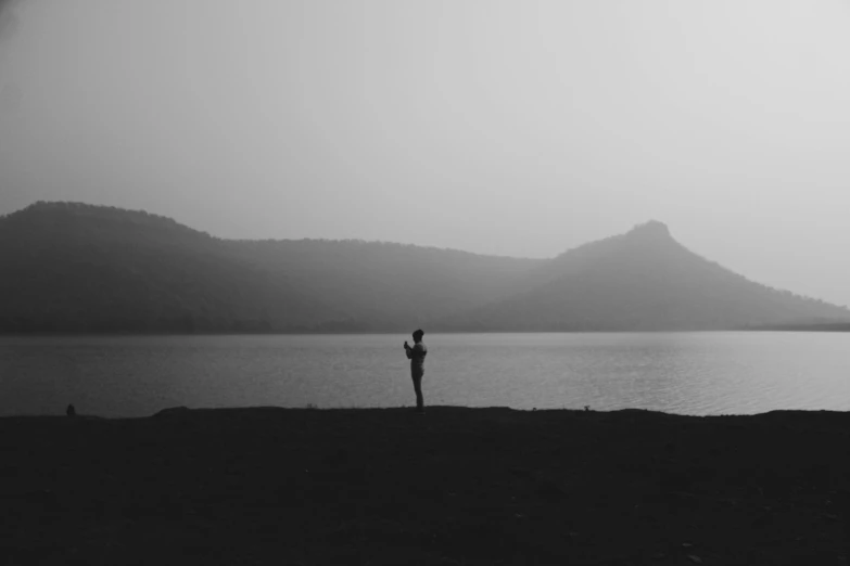 a person standing on a beach by the water in the fog