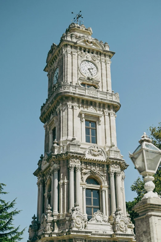 a stone clock tower with statue, tree and clear blue sky