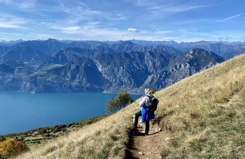 a man with backpack on hiking up a hill overlooking a lake