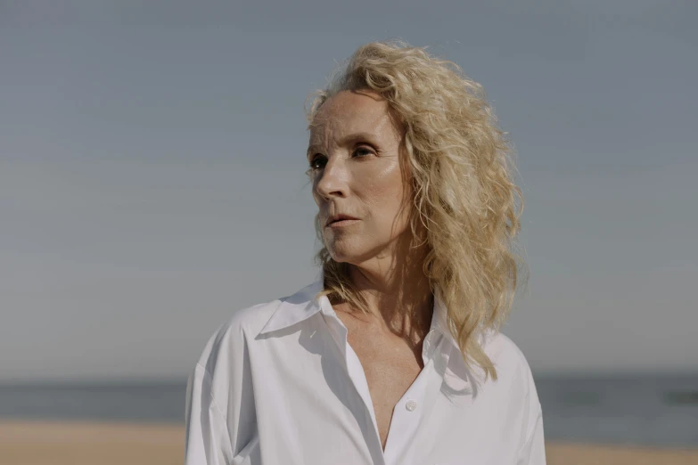 a blonde woman with long hair standing on a beach