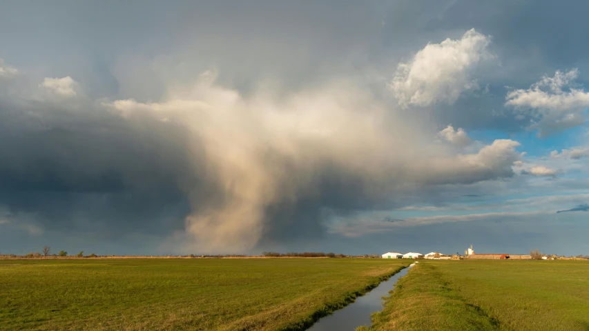 a beautiful cloud formation looms over a green grassy field