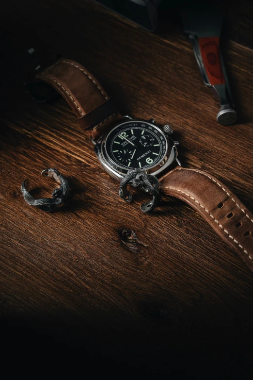 a watch sits on top of a brown leather strap